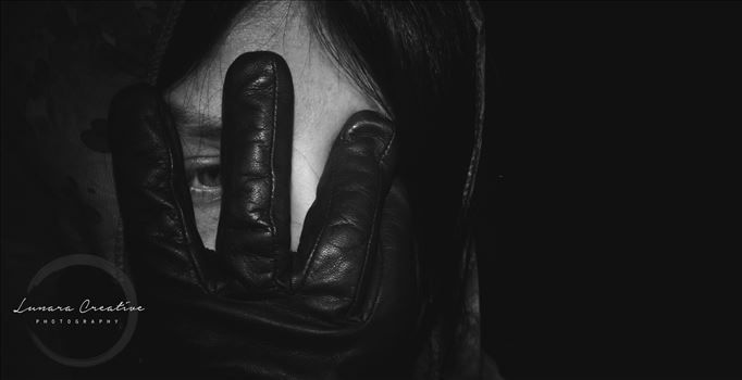 Hidden - A woman dressed in a cloak and black gloves hides her face.  Whether she hides her face in shame or fear is unknown.