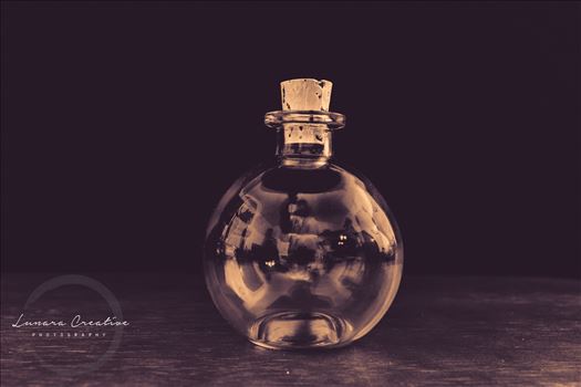 Tiny Bottle - A tiny bottle sitting on a table.  Photo was tinted with a hint of purple color.